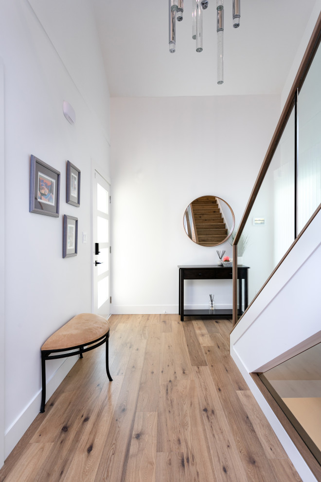 Example of a mid-sized transitional medium tone wood floor and brown floor front door design in Vancouver with white walls and a glass front door
