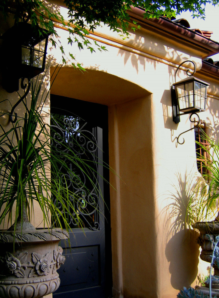 Photo of a mid-sized mediterranean front door in Santa Barbara with a single front door, a black front door and yellow walls.