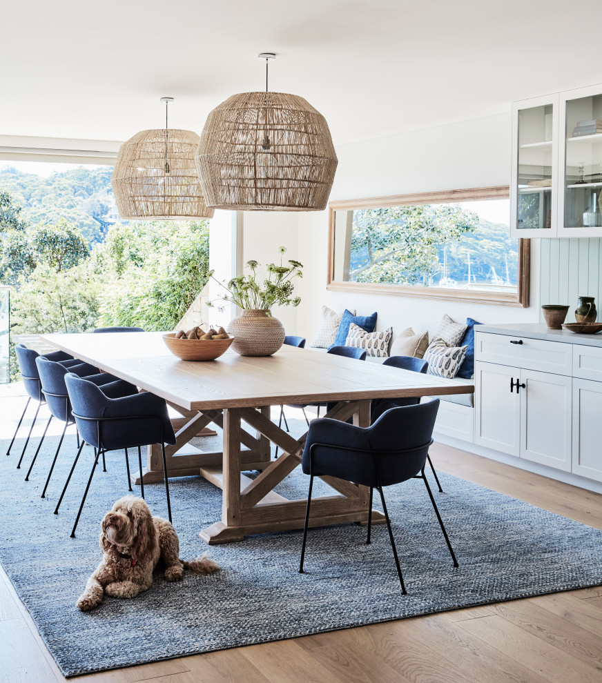 Inspiration for a mid-sized beach style open plan dining in Sydney with white walls, light hardwood floors and panelled walls.