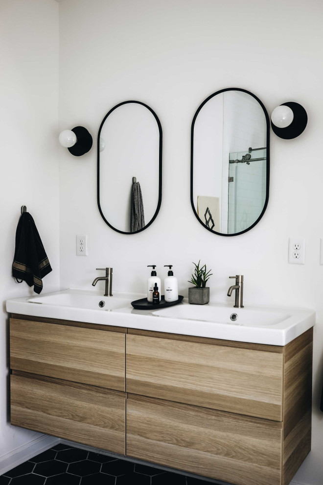 На фото: главная ванная комната среднего размера в стиле модернизм с плоскими фасадами, светлыми деревянными фасадами, отдельно стоящей ванной, душевой комнатой, унитазом-моноблоком, белой плиткой, керамической плиткой, белыми стенами, полом из керамической плитки, монолитной раковиной, черным полом, душем с раздвижными дверями, тумбой под две раковины и подвесной тумбой с