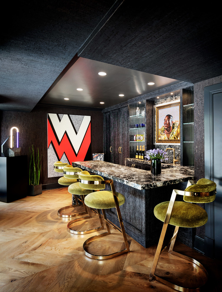 Contemporary u-shaped wet bar in New York with flat-panel cabinets, black cabinets, black splashback, medium hardwood floors, brown floor and black benchtop.