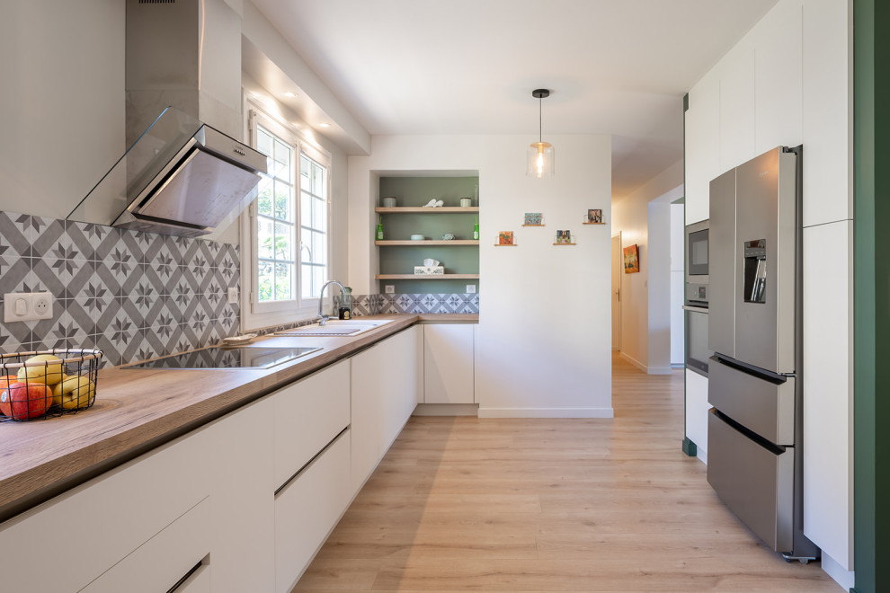 Inspiration for a large scandinavian single-wall eat-in kitchen in Other with a double-bowl sink, beaded inset cabinets, white cabinets, laminate benchtops, grey splashback, cement tile splashback, stainless steel appliances and light hardwood floors.