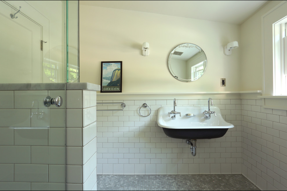 This is an example of a bathroom in Portland with white cabinets, a corner shower, white tile, ceramic tile, white walls, marble floors, a wall-mount sink, grey floor and a hinged shower door.