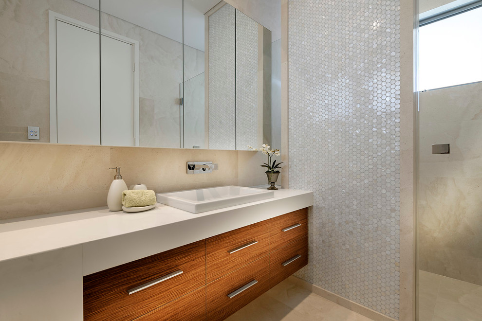 Large modern bathroom in Perth with a drop-in sink, white cabinets, limestone benchtops, a freestanding tub, beige tile, mosaic tile, beige walls and limestone floors.