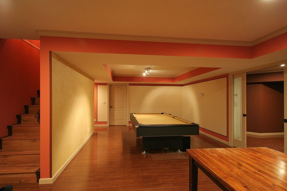 Inspiration for a mid-sized transitional underground medium tone wood floor and brown floor basement remodel in Vancouver with orange walls, a standard fireplace and a stone fireplace