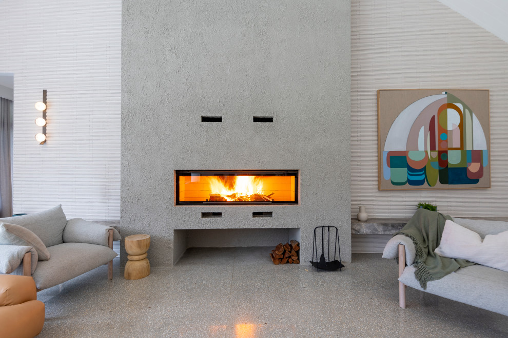 Expansive modern open concept living room in Melbourne with grey walls, concrete floors and a standard fireplace.