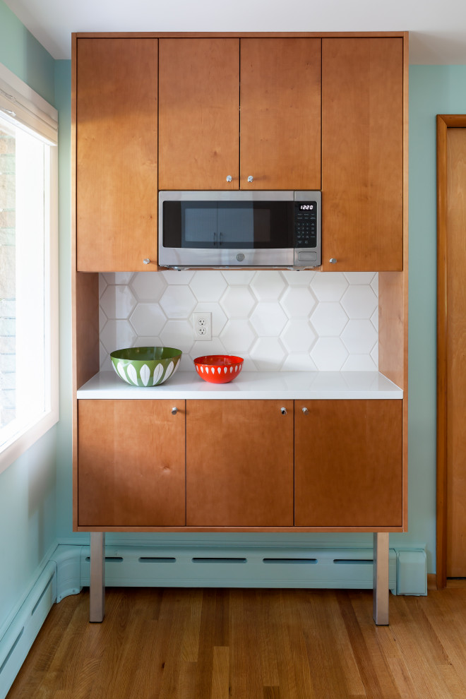 Photo of a mid-sized midcentury l-shaped eat-in kitchen in Seattle with an undermount sink, flat-panel cabinets, white cabinets, quartz benchtops, white splashback, ceramic splashback, light hardwood floors, with island, brown floor, white benchtop and stainless steel appliances.