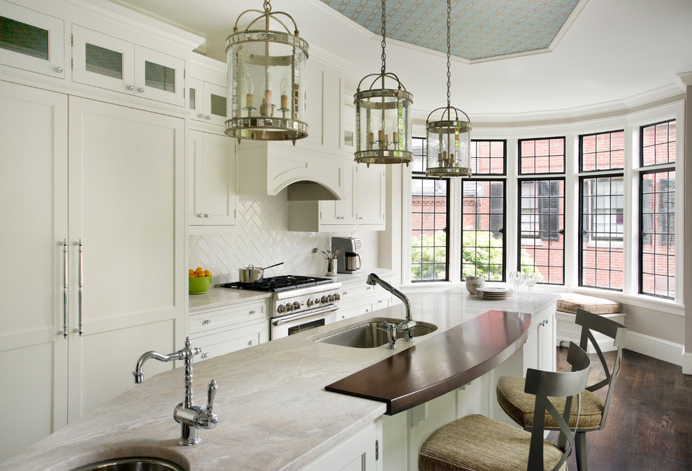 Photo of a large traditional galley kitchen in Boston with an undermount sink, shaker cabinets, white cabinets, marble benchtops, white splashback, ceramic splashback, panelled appliances, dark hardwood floors and with island.