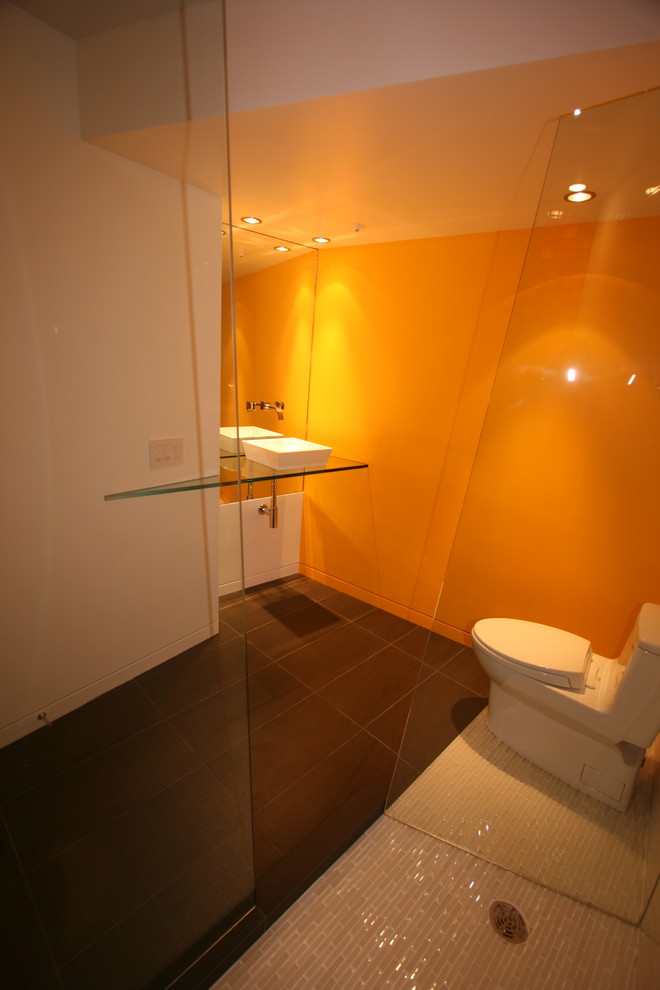 Large modern bathroom in San Francisco with a pedestal sink, open cabinets, glass benchtops, a corner shower, a one-piece toilet, gray tile, stone tile, orange walls and slate floors.