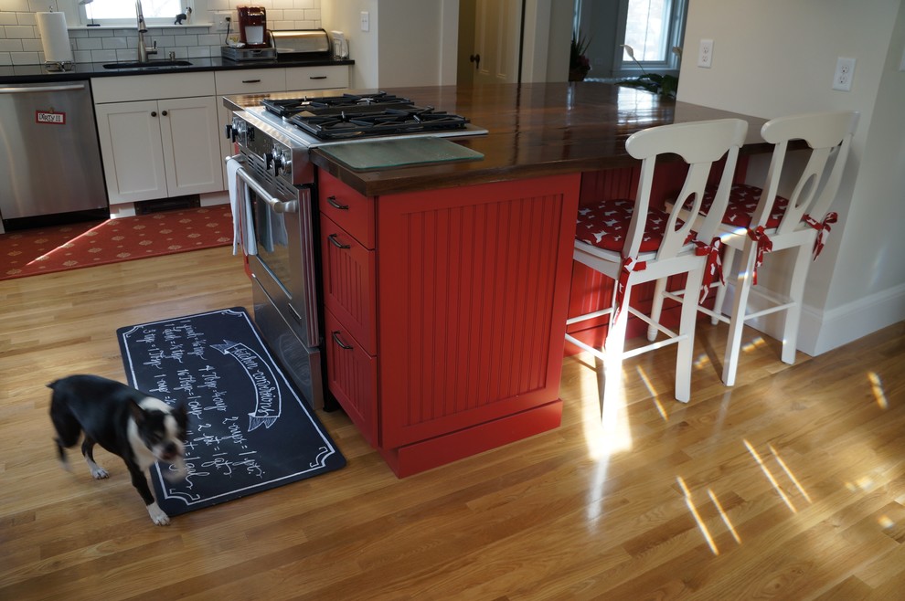 Enclosed kitchen - small rustic l-shaped light wood floor and beige floor enclosed kitchen idea in Boston with an undermount sink, recessed-panel cabinets, granite countertops, white backsplash, subway tile backsplash, stainless steel appliances, an island, white cabinets and black countertops