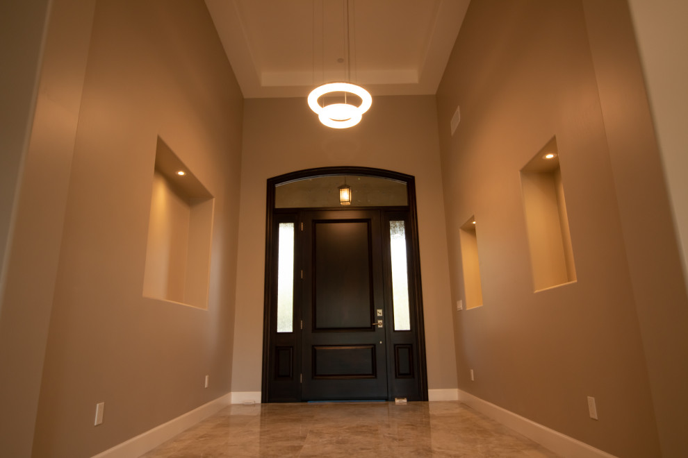 This is an example of a mid-sized contemporary foyer in Phoenix with beige walls, porcelain floors, a single front door, a black front door and beige floor.