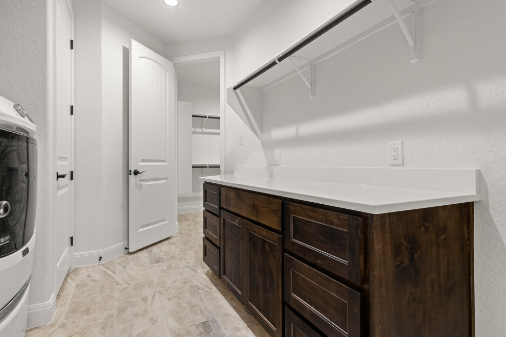 Transitional utility room in Austin with brown cabinets, granite benchtops, a side-by-side washer and dryer and white benchtop.
