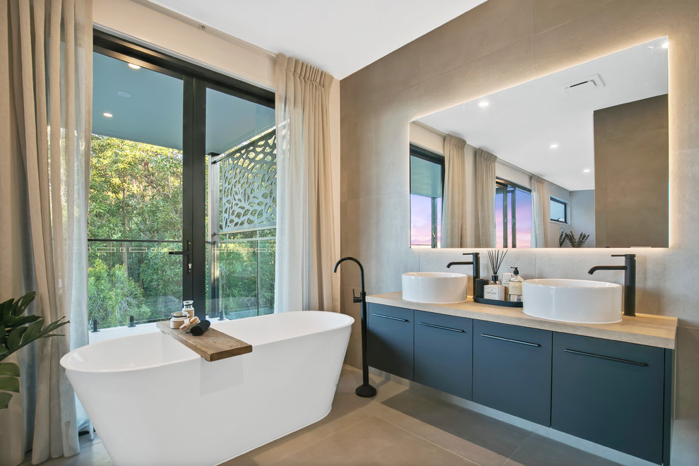 Photo of a contemporary master bathroom in Sunshine Coast with flat-panel cabinets, grey cabinets, a freestanding tub, gray tile, white walls, a vessel sink, wood benchtops, grey floor and beige benchtops.