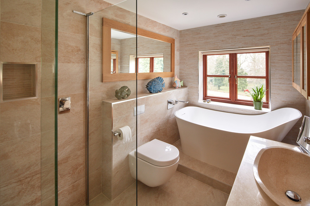 Small contemporary master bathroom in Hertfordshire with a freestanding tub, an open shower, a wall-mount toilet, beige tile, beige walls, a vessel sink and an open shower.