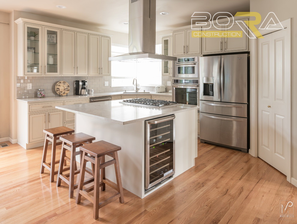 Inspiration for a mid-sized transitional l-shaped eat-in kitchen remodel with an undermount sink, recessed-panel cabinets, beige cabinets, quartz countertops, gray backsplash, ceramic backsplash, stainless steel appliances and an island