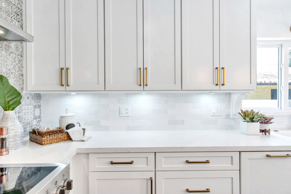 Mid-sized transitional l-shaped open concept kitchen photo in Miami with shaker cabinets, white cabinets, quartz countertops, gray backsplash, porcelain backsplash, stainless steel appliances, an island and white countertops