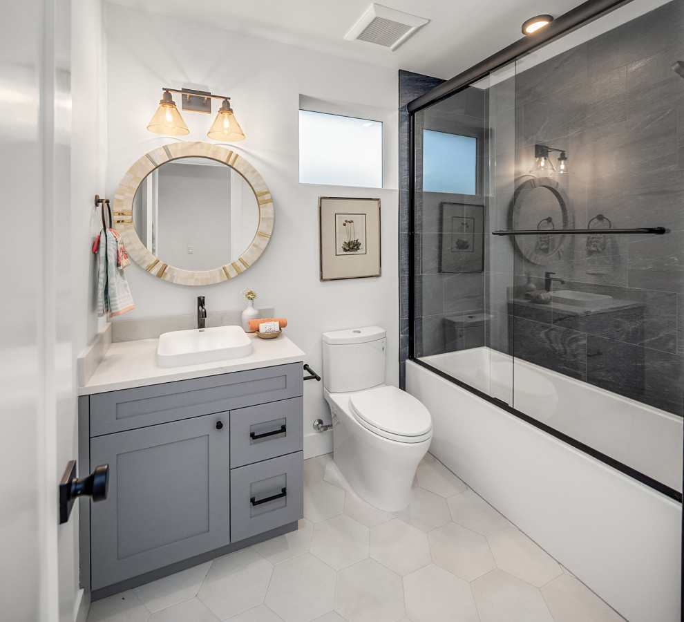 Идея дизайна: маленькая детская ванная комната в морском стиле с фасадами с утопленной филенкой, синими фасадами, ванной в нише, раздельным унитазом, черной плиткой, керамогранитной плиткой, белыми стенами, полом из керамогранита, накладной раковиной, столешницей из кварцита, серым полом, душем с раздвижными дверями, белой столешницей, тумбой под одну раковину и встроенной тумбой для на участке и в саду