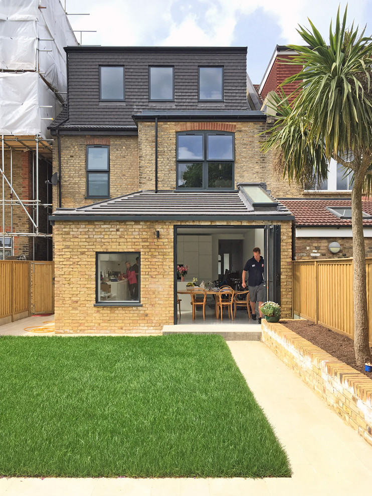This is an example of a mid-sized contemporary three-storey brick yellow exterior in London with a hip roof.