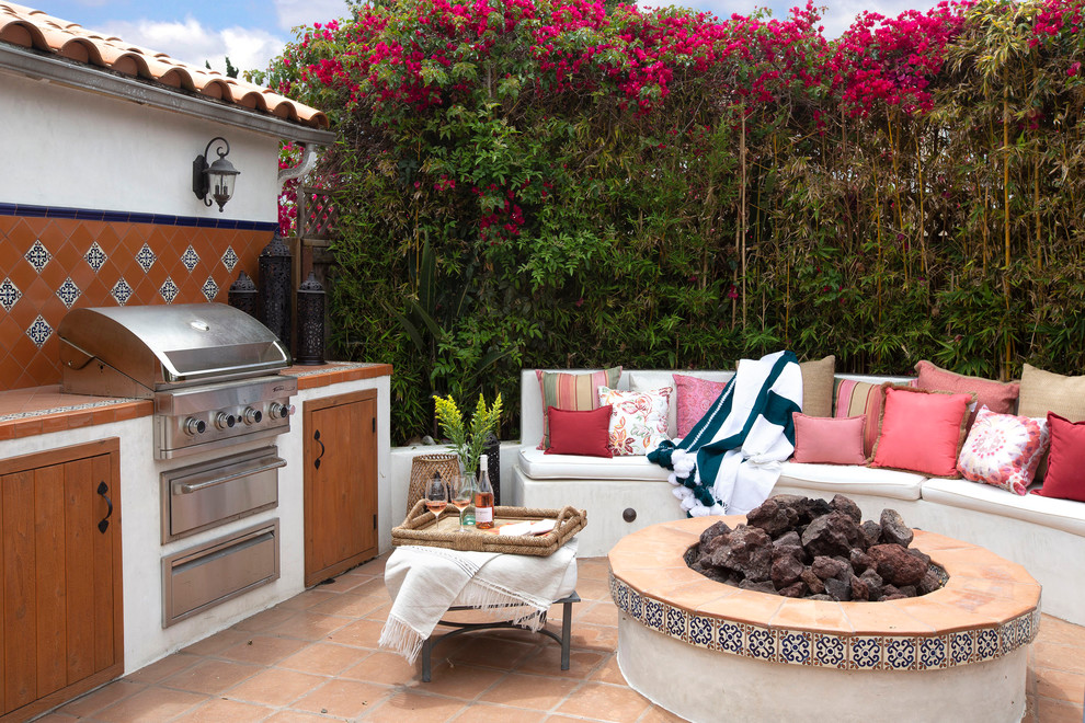 This is an example of a mediterranean backyard patio in San Diego with a fire feature, tile and no cover.
