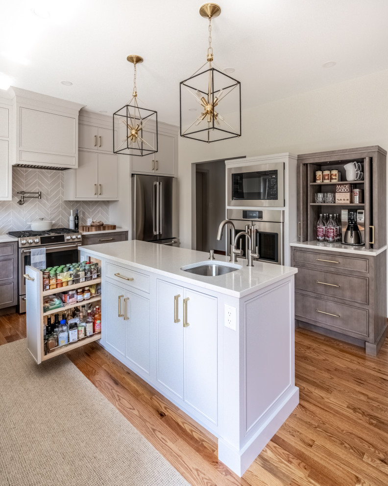 This is an example of a mid-sized transitional l-shaped eat-in kitchen in Philadelphia with an undermount sink, flat-panel cabinets, beige cabinets, quartz benchtops, beige splashback, ceramic splashback, stainless steel appliances, dark hardwood floors, with island, brown floor and white benchtop.