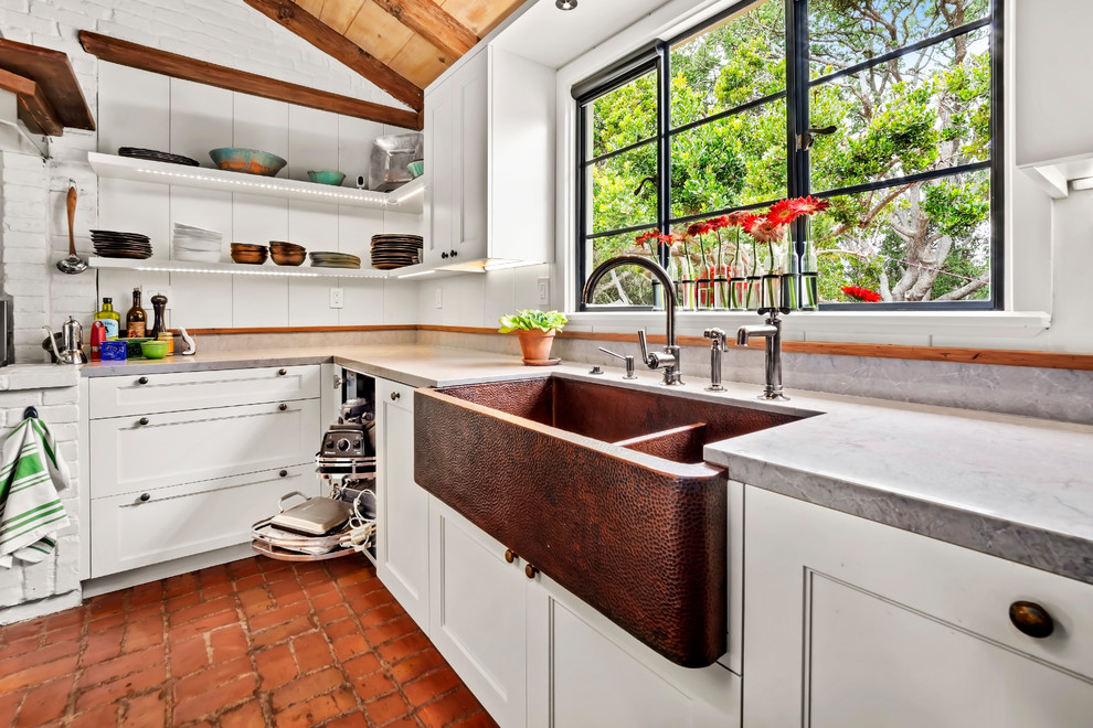 Photo of a large arts and crafts u-shaped eat-in kitchen in Other with a farmhouse sink, recessed-panel cabinets, white cabinets, brick floors, with island and grey benchtop.