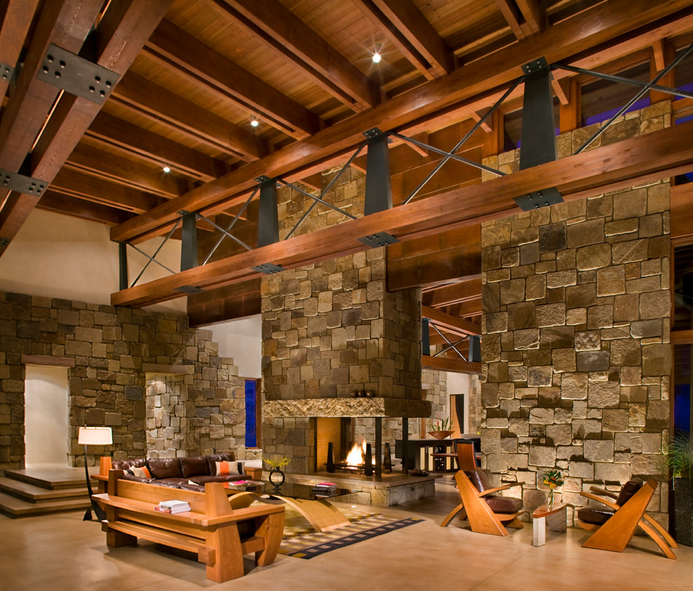 This is an example of a large contemporary formal open concept living room in Denver with concrete floors, beige walls, a two-sided fireplace, a stone fireplace surround and no tv.