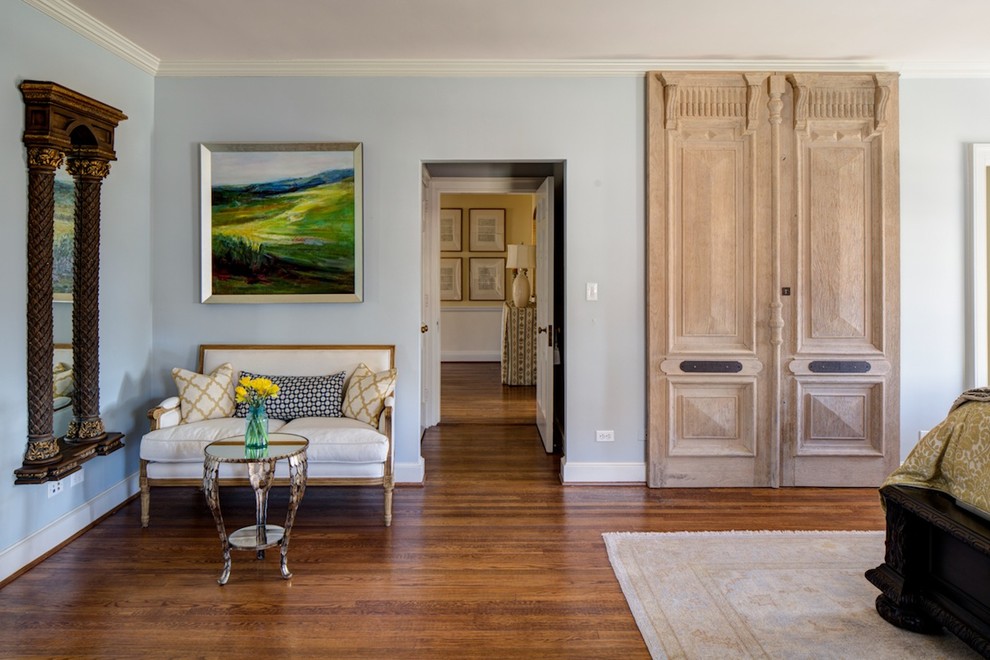 This is an example of a large traditional master bedroom in Charleston with blue walls, dark hardwood floors, a standard fireplace, a wood fireplace surround and brown floor.