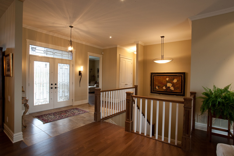 This is an example of a large transitional foyer in Ottawa with black walls, limestone floors, a double front door and a glass front door.