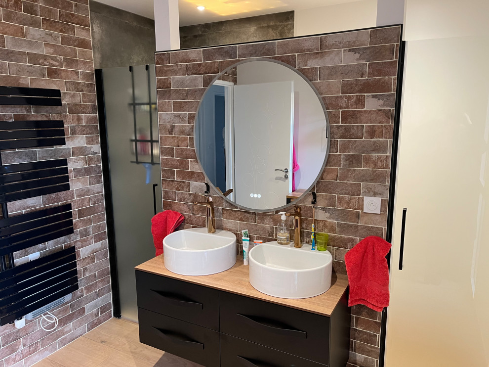 Photo of a modern ensuite bathroom in Clermont-Ferrand with an alcove shower, a wall mounted toilet, ceramic flooring, a built-in sink, wooden worktops, an enclosed toilet, double sinks, a floating vanity unit and brick walls.