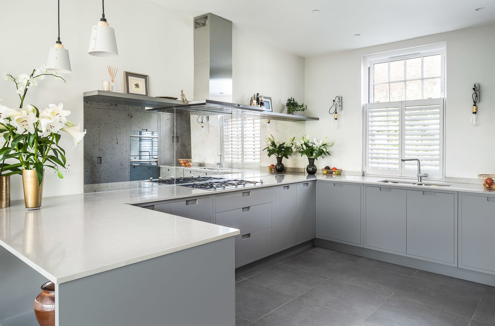 This is an example of a modern u-shaped kitchen in London with flat-panel cabinets, grey cabinets, white splashback, stainless steel appliances and grey floor.
