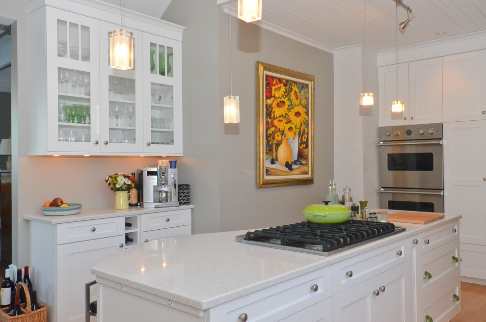 Inspiration for a large transitional open plan kitchen in Jacksonville with recessed-panel cabinets, white cabinets, terrazzo benchtops, stainless steel appliances, light hardwood floors, with island and white benchtop.