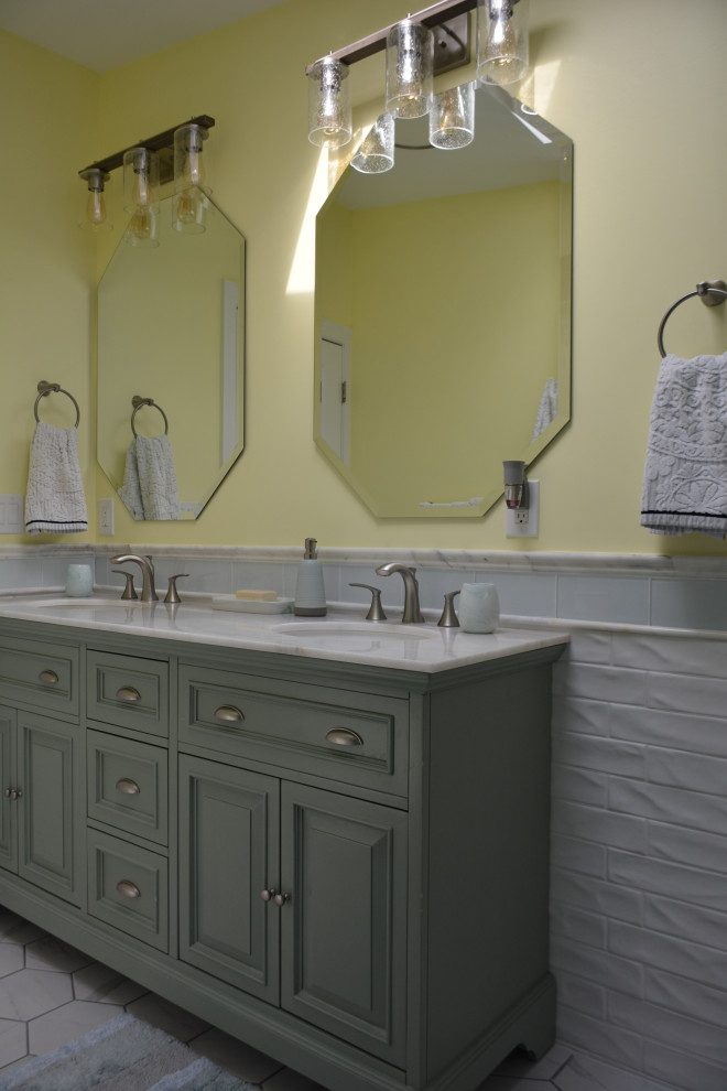 Mid-sized beach style kids bathroom in New York with raised-panel cabinets, green cabinets, an alcove tub, a shower/bathtub combo, a one-piece toilet, white tile, ceramic tile, yellow walls, ceramic floors, an undermount sink, marble benchtops, white floor, a shower curtain, white benchtops, a double vanity, a freestanding vanity and vaulted.