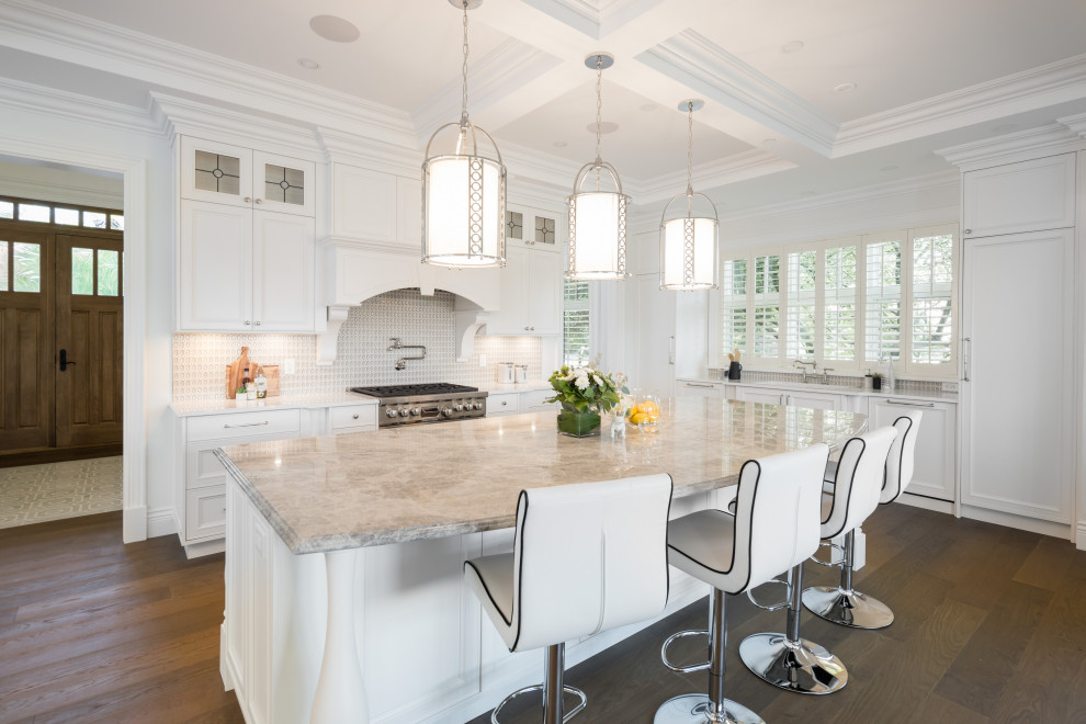 This is an example of a traditional u-shaped kitchen in Vancouver with an undermount sink, recessed-panel cabinets, white cabinets, marble benchtops, grey splashback, glass tile splashback, panelled appliances, medium hardwood floors, with island, brown floor, beige benchtop and coffered.