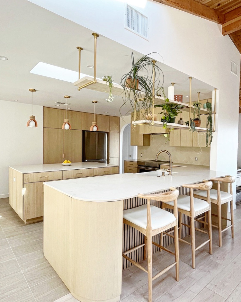 Mid-sized contemporary u-shaped eat-in kitchen in Los Angeles with an undermount sink, flat-panel cabinets, light wood cabinets, quartz benchtops, beige splashback, cement tile splashback, stainless steel appliances, porcelain floors, with island, beige floor and white benchtop.
