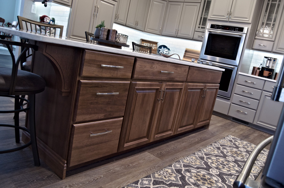 U-shaped brown floor eat-in kitchen photo with a double-bowl sink, raised-panel cabinets, gray cabinets, marble countertops, white backsplash, stainless steel appliances, an island and white countertops