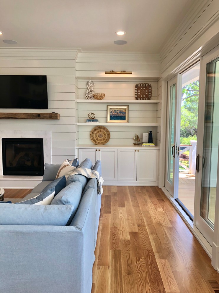 This is an example of a large country formal open concept living room in Charleston with a wall-mounted tv, white walls, medium hardwood floors, a standard fireplace, a plaster fireplace surround and brown floor.