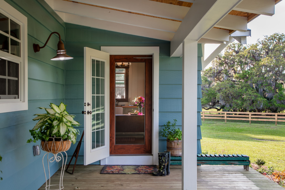 Réalisation d'un grand porche d'entrée de maison avant champêtre avec des colonnes, une terrasse en bois et une extension de toiture.