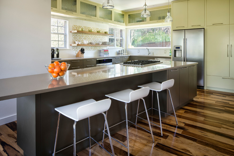 Contemporary eat-in kitchen in Austin with grey cabinets, solid surface benchtops, medium hardwood floors and with island.