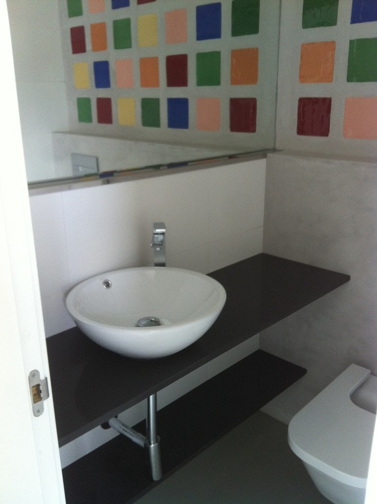 This is an example of a small modern powder room in Other with open cabinets, a one-piece toilet, multi-coloured walls and a vessel sink.