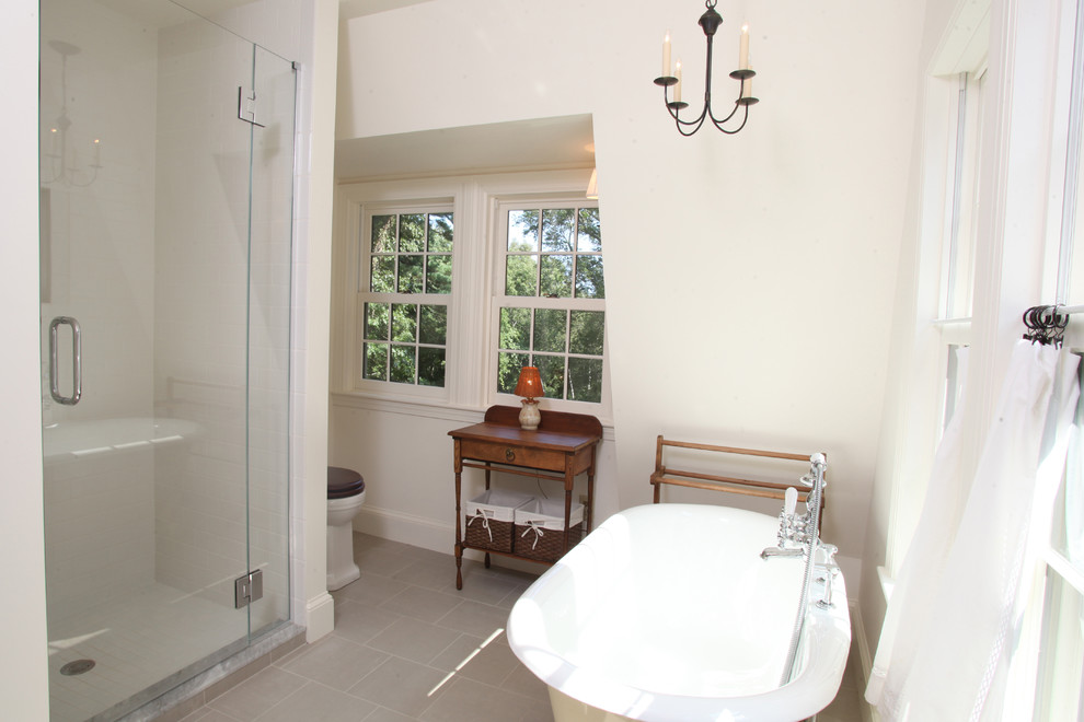 Photo of a bathroom in Boston with a claw-foot tub, an alcove shower, a two-piece toilet, gray tile, ceramic tile, white walls and porcelain floors.