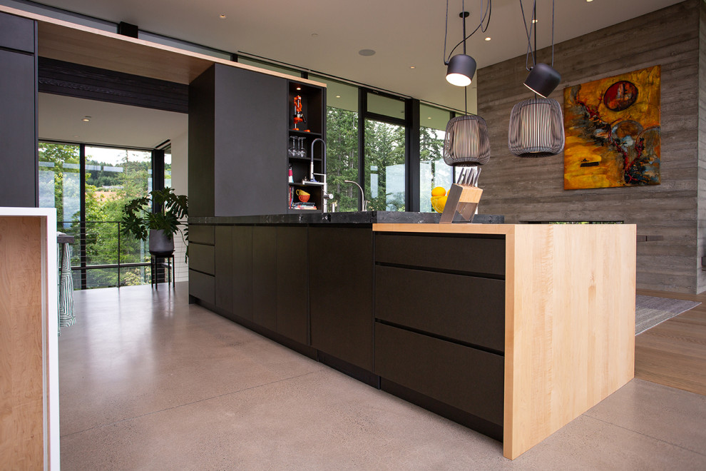 Design ideas for a modern l-shaped eat-in kitchen in Portland with flat-panel cabinets, black cabinets, wood benchtops, with island, a drop-in sink, stainless steel appliances, concrete floors, grey floor and multi-coloured benchtop.