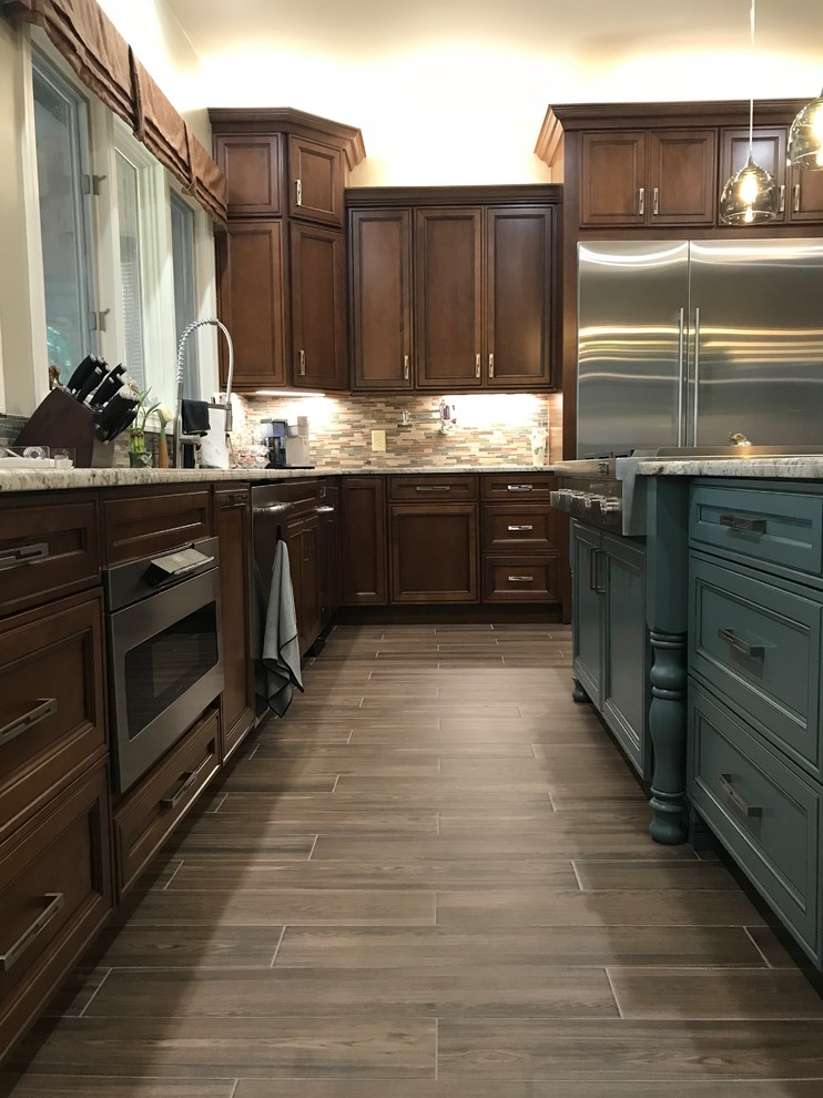 This is an example of a large traditional u-shaped separate kitchen in Raleigh with an undermount sink, recessed-panel cabinets, dark wood cabinets, granite benchtops, multi-coloured splashback, matchstick tile splashback, stainless steel appliances, dark hardwood floors, with island, brown floor and grey benchtop.