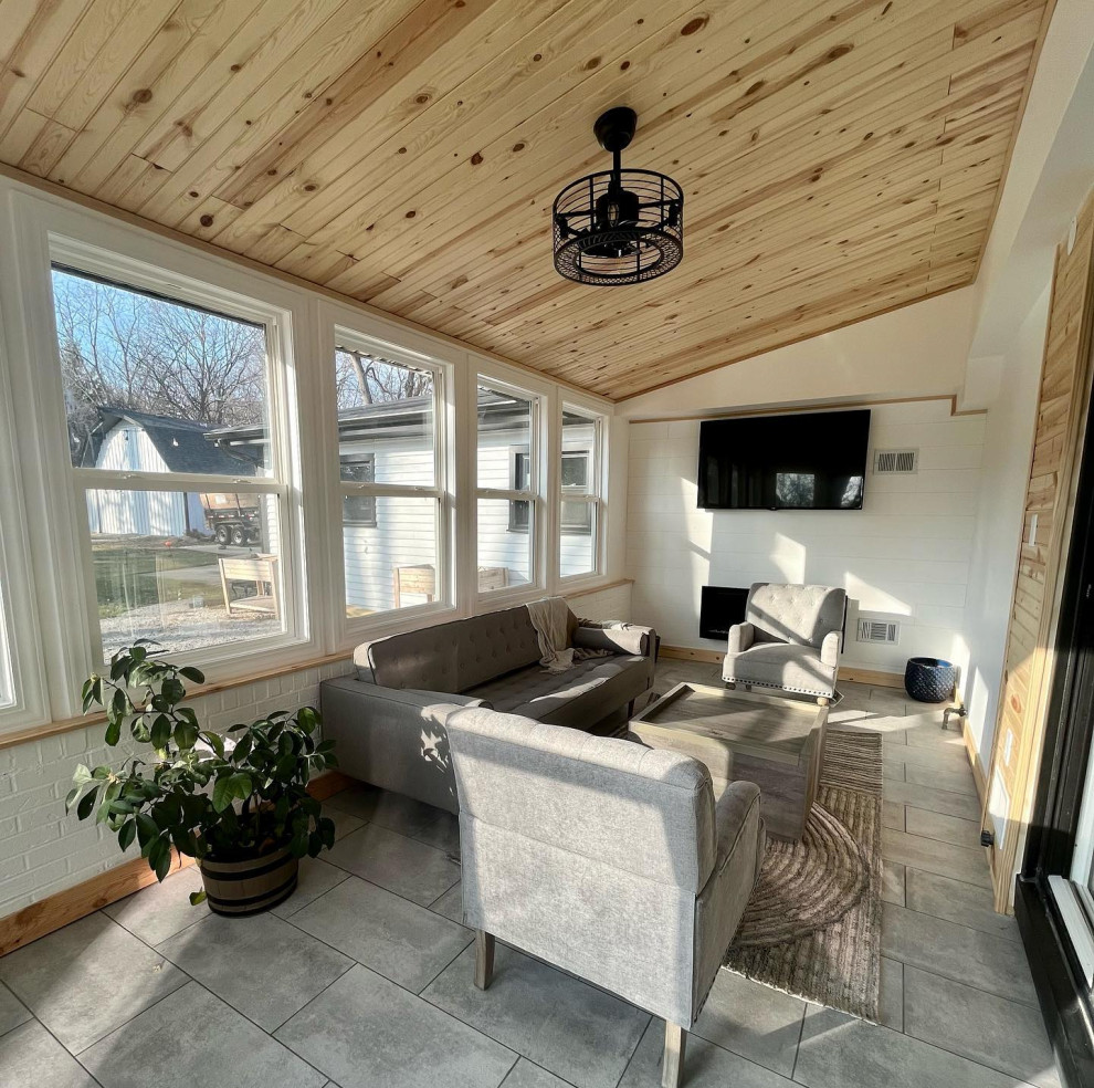 Photo of a mid-sized country sunroom in Chicago with ceramic floors, a standard fireplace, a standard ceiling and grey floor.