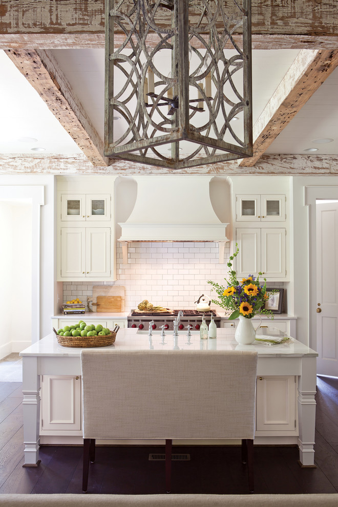 Inspiration for a traditional galley kitchen in San Francisco with a farmhouse sink, recessed-panel cabinets, white cabinets, white splashback, subway tile splashback, dark hardwood floors, with island, brown floor and white benchtop.