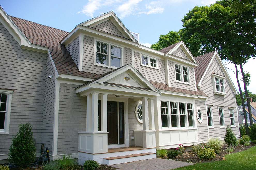This is an example of a large traditional two-storey beige house exterior in Boston with wood siding, a gable roof and a shingle roof.