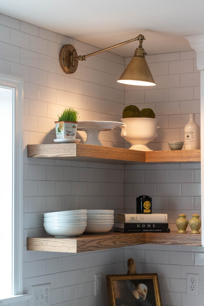 Example of a mid-sized transitional l-shaped medium tone wood floor and brown floor open concept kitchen design with an undermount sink, shaker cabinets, white cabinets, quartzite countertops, white backsplash, ceramic backsplash, white appliances, an island and white countertops