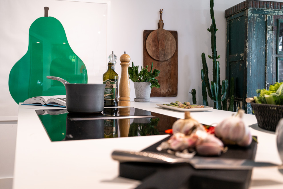 Immagine di una cucina minimalista di medie dimensioni con lavello da incasso, ante lisce, ante bianche, top in quarzite, paraspruzzi verde, paraspruzzi in granito, elettrodomestici neri, parquet chiaro, pavimento marrone, top bianco e soffitto ribassato
