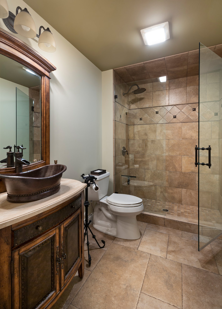 Photo of a mid-sized country 3/4 bathroom with shaker cabinets, dark wood cabinets, an alcove shower, a one-piece toilet, beige tile, white walls, a vessel sink, beige floor, a hinged shower door and beige benchtops.