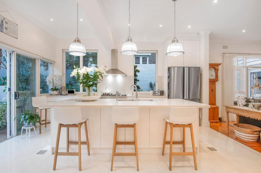 Photo of a large traditional single-wall kitchen/diner in DC Metro with a submerged sink, flat-panel cabinets, white cabinets, engineered stone countertops, white splashback, terrazzo flooring, an island and white worktops.
