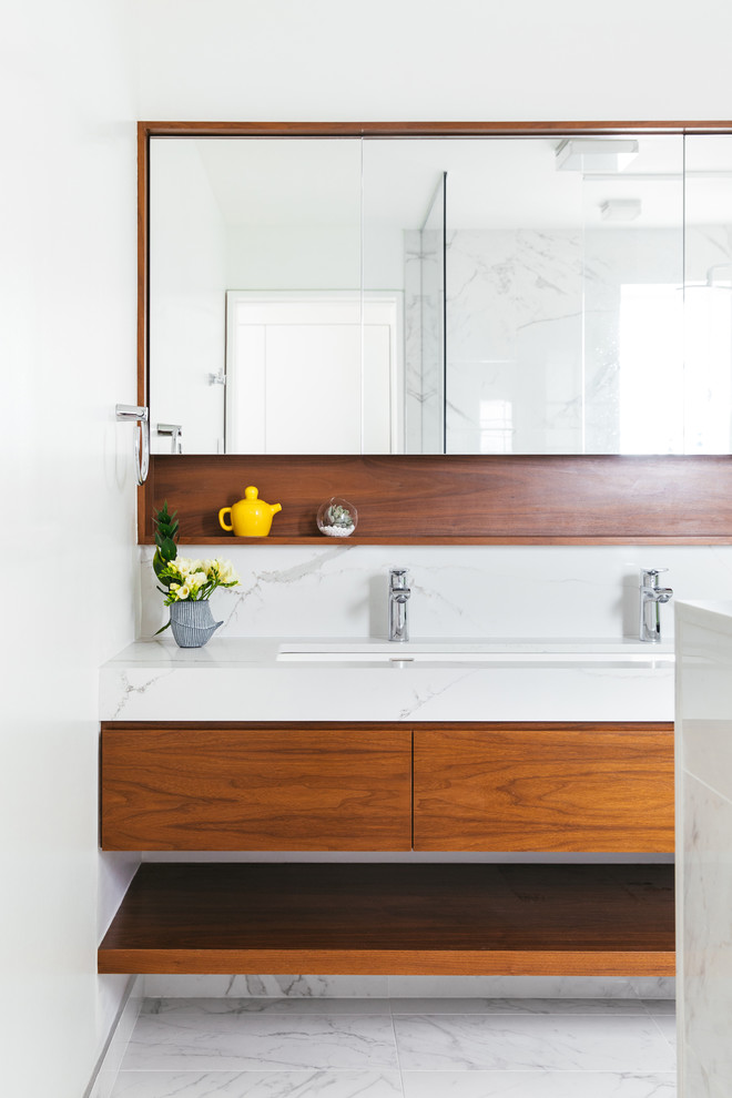 Contemporary bathroom in New York with flat-panel cabinets, white tile, white walls, a trough sink, white floor, white benchtops, dark wood cabinets and engineered quartz benchtops.